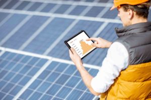 Engineer using tablet to examine solar panel