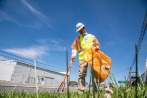 Worker picking up trash alongside road