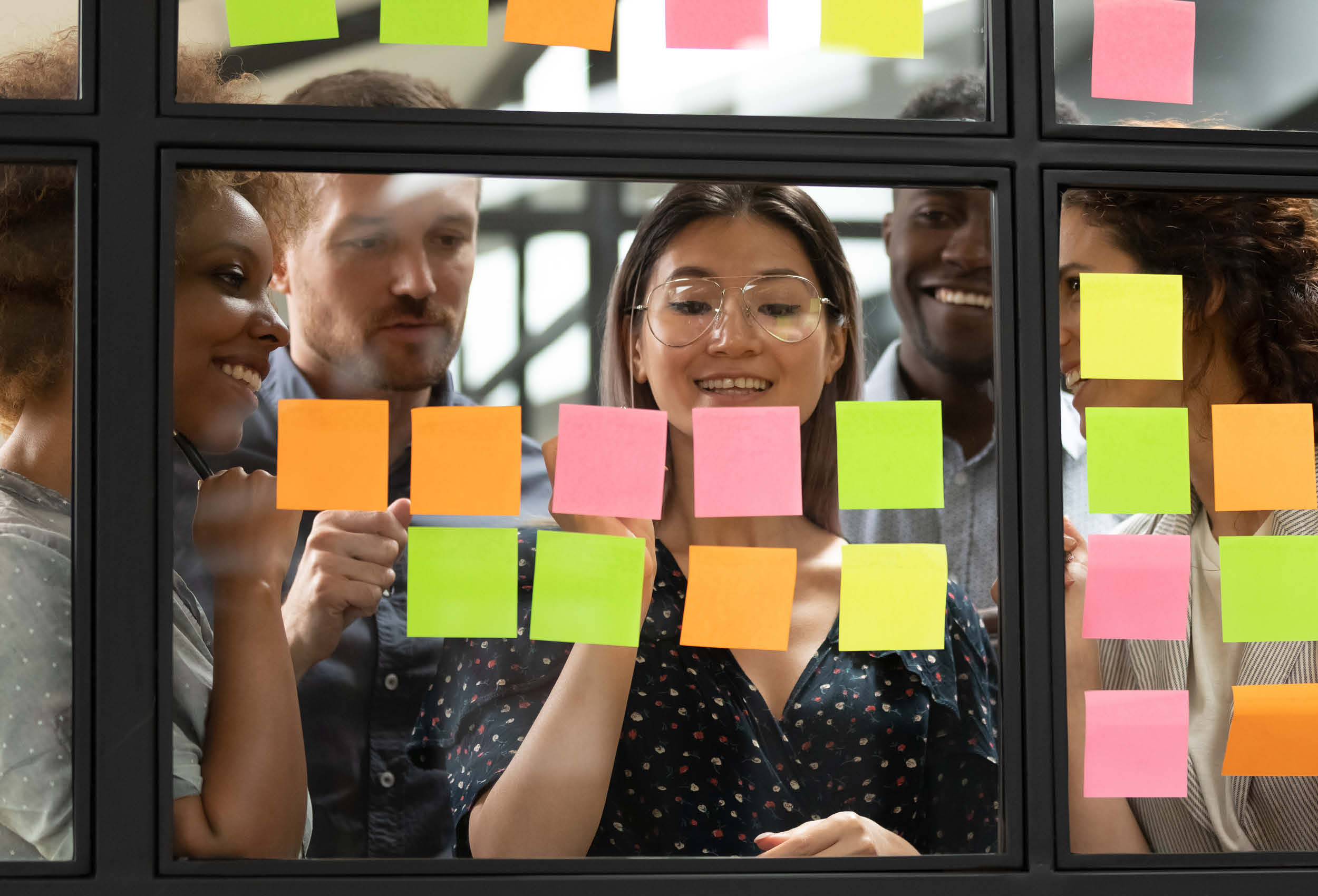 Managers brainstorm with post it notes on window.