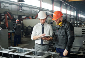 Young master and bearded engineer in hardhat discuss plans