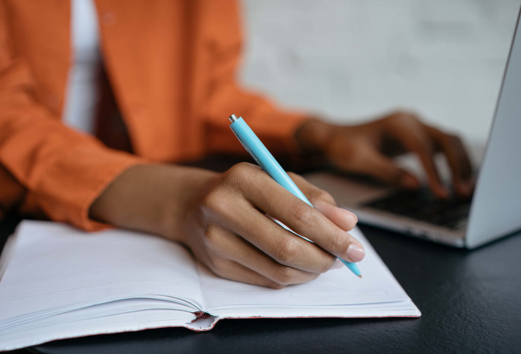 Student hand writing with pen on paper