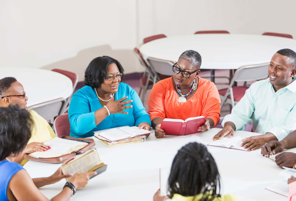 Women chat around a table at meeting.