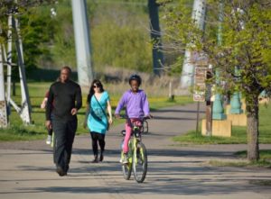 Young child biking along with adults walking