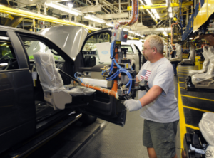 Manufacturing plant with worker putting together a car