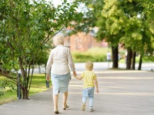 Elderly woman holding a child's hand while they walk.