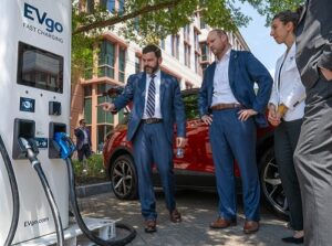 Three people looking at an EV charging station.