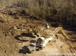 Two large pieces of machinery digging through fallen trees.